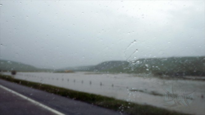 A flooded valley, with water approaching the highway.