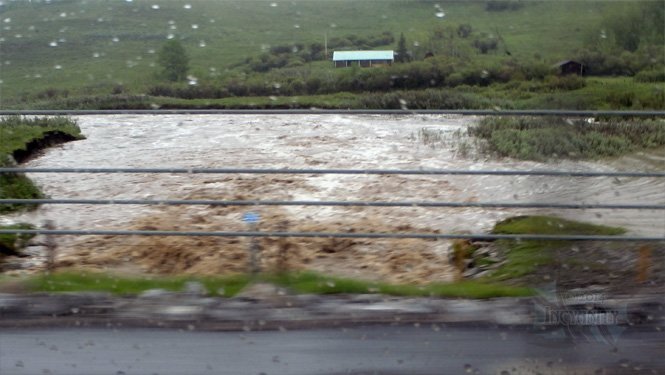 A burst creek chewing away the highway.